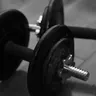 Adjustable plate dumbbells on a floor, black and white (illustrative photo)