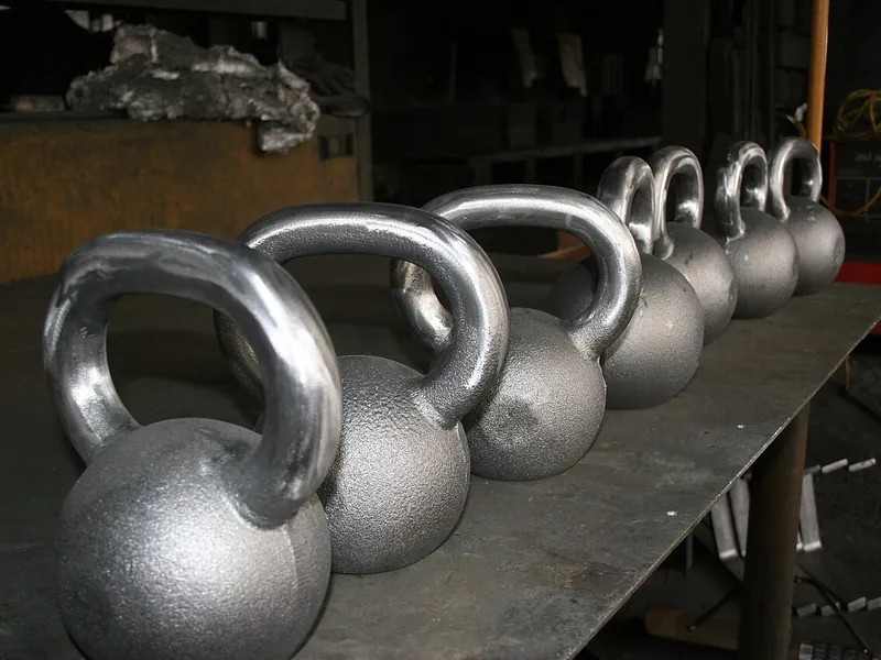 Row of steel kettlebells on a workbench (illustrative photo)