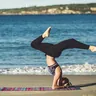 Person in a headstand pose on a yoga mat on the beach (illustrative photo)