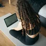 Woman following a class on a laptop from her exercise mat (illustrative photo)