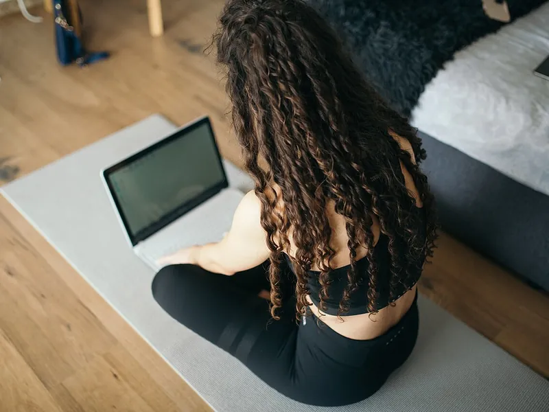 Woman following a class on a laptop from her exercise mat (illustrative photo)
